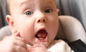 Maluch z otwartymi ustami, pokazujący pierwszy ząbek. Czy to ząbkowanie czy przeziębienie?