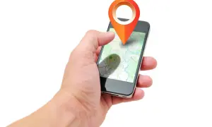Dłoń trzyma smartfon z mapą i ikoną lokalizacji. Aplikacja pokazuje, jak działa lokalizator, gdzie jest dziecko.