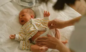 Mama zmienia pieluchę noworodkowi. Jakie pieluchy dla noworodka wybrać, by maluszkowi było wygodnie?