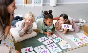 Dzieci uczą się liter z nauczycielką. Zastanawiasz się, ile kosztuje dodatkowa godzina w przedszkolu?