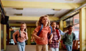 Radosne dzieci z plecakami biegną szkolnym korytarzem. Czy zerówka ma ferie? Wygląda na to, że tak!