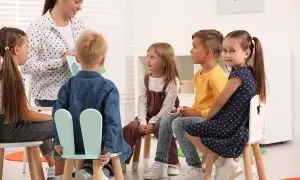 Nauczycielka czyta dzieciom książkę. Grupa przedszkolna liczy 6 dzieci.