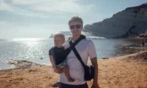 Ojciec z niemowlakiem na plaży, idealne miejsce, gdzie na wakacje z niemowlakiem. Słońce, morze i białe klify tworzą piękne tło.