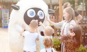 Dzieci dotykają pluszowej owcy, szukając pomysłu, gdzie na weekend z dzieckiem. Radość i zabawa na świeżym powietrzu.