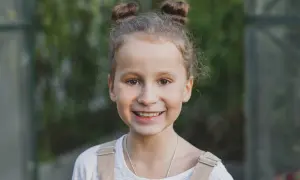 Uśmiechnięta dziewczynka z dwoma kucykami. Waga siedmiolatki jest kwestią indywidualną, ale zdrowa dziewczynka w tym wieku waży zazwyczaj ok. 20-30 kg.