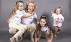 Uśmiechnięta pani z przedszkola prywatnego, otoczona dziećmi. Ile godzin pracuje nauczyciel w przedszkolu prywatnym? Tyle, ile potrzeba, by dać im radość!