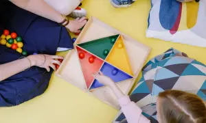 Dzieci bawią się kolorowymi kulkami w żłobku. Zastanawiasz się, ile zarabia pomoc w żłobku?