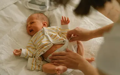 Mama zmienia pieluchę noworodkowi. Jakie pieluchy dla noworodka wybrać, by maluszkowi było wygodnie?