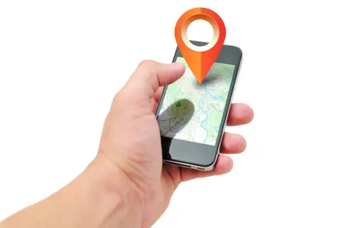 Dłoń trzyma smartfon z mapą i ikoną lokalizacji. Aplikacja pokazuje, jak działa lokalizator, gdzie jest dziecko.