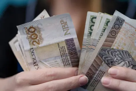 Ręce trzymające banknoty 200 zł. Czy to odpowiedź na pytanie, ile zarabia dyrektor żłobka?