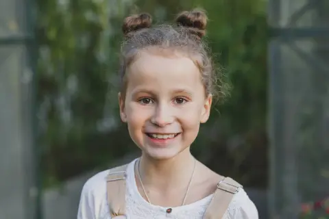 Uśmiechnięta dziewczynka z dwoma kucykami. Waga siedmiolatki jest kwestią indywidualną, ale zdrowa dziewczynka w tym wieku waży zazwyczaj ok. 20-30 kg.