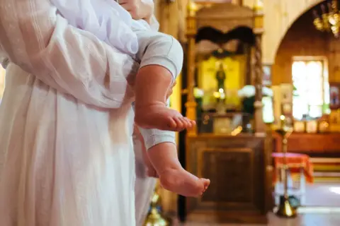 Dziecko w kościele, czy rodzic może być świadkiem bierzmowania? W tle ołtarz i ikony.
