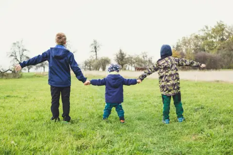 Trzech chłopców trzyma się za ręce na łące. Zastanawiasz się, ile powinien ważyć sześcioletni chłopiec?