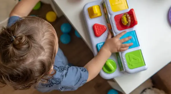 Dziecko bawi się zabawką edukacyjną. Zastanawiasz się, ile kosztuje żłobek miesięcznie?