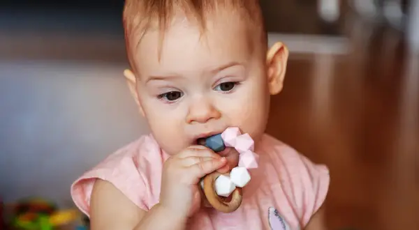 Maluch gryzie gryzak, bo ząbkuje. To naturalne, **dlaczego dziecko gryzie przedmioty**, gdy rosną mu zęby.
