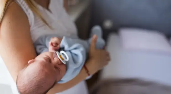 Mama tuli otula noworodka ze smoczkiem. Czy dziecko może spać ze smoczkiem? To pytanie nurtuje wielu rodziców.