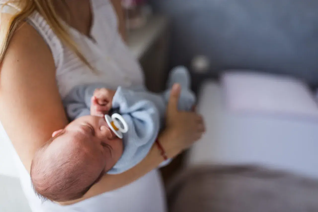 Mama tuli otula noworodka ze smoczkiem. Czy dziecko może spać ze smoczkiem? To pytanie nurtuje wielu rodziców.