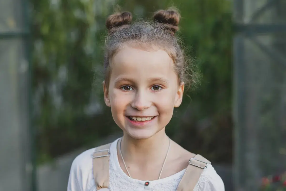 Uśmiechnięta dziewczynka z dwoma kucykami. Waga siedmiolatki jest kwestią indywidualną, ale zdrowa dziewczynka w tym wieku waży zazwyczaj ok. 20-30 kg.
