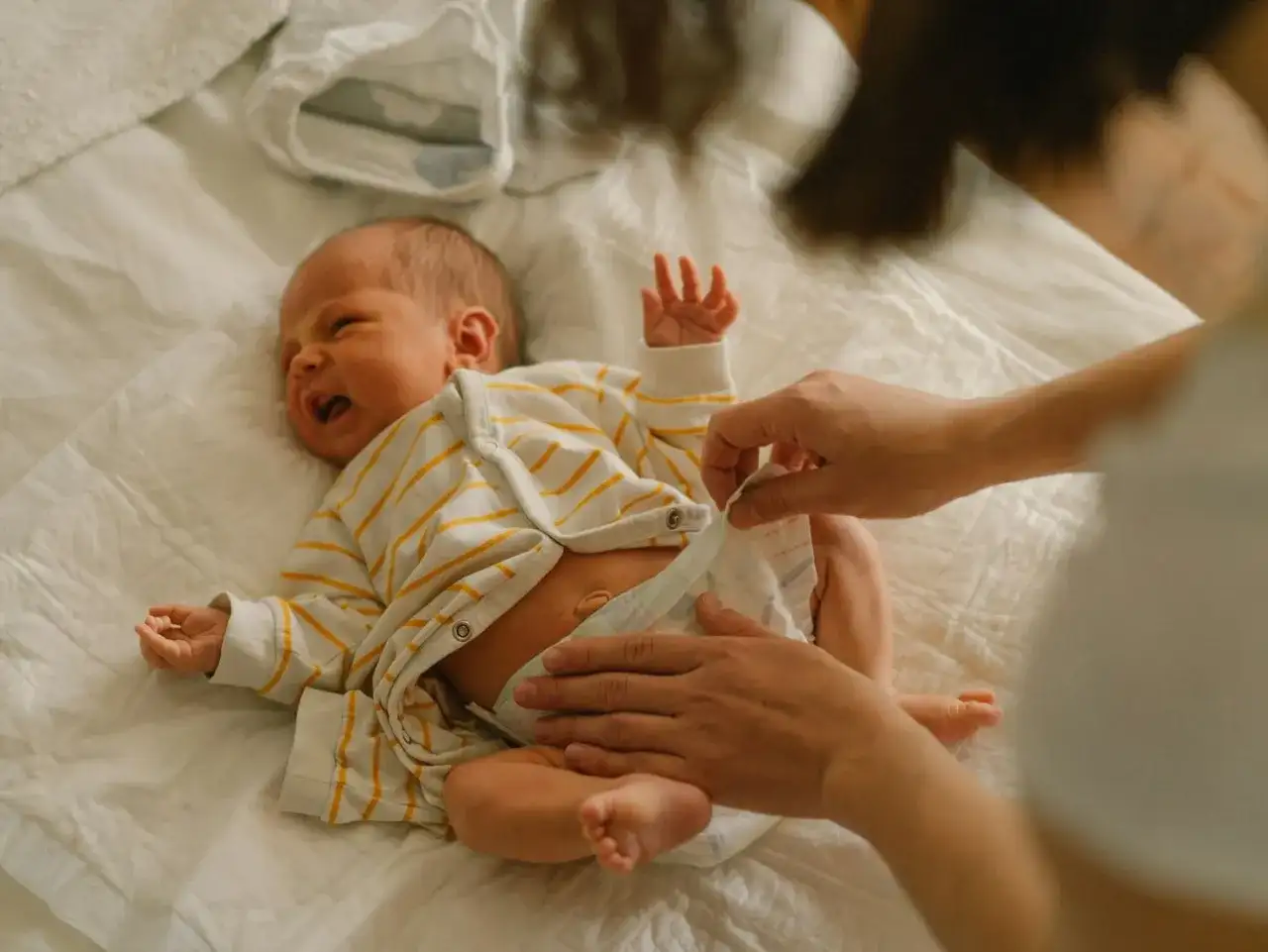 Mama zmienia pieluchę noworodkowi. Jakie pieluchy dla noworodka wybrać, by maluszkowi było wygodnie?