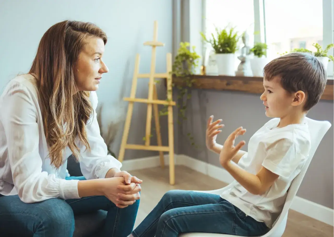 Kiedy z dzieckiem do psychiatry. Rozmowa terapeuty z małym pacjentem, który gestykuluje, opowiadając o swoich uczuciach.