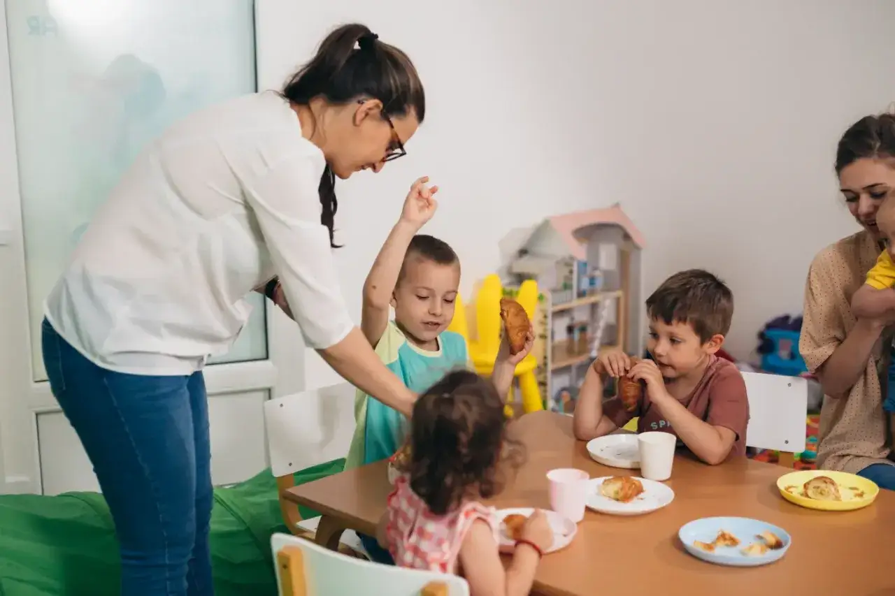 Przedszkolanka wita dzieci na śniadaniu. Dzieci jedzą rogaliki, a ona pilnuje, by każdy miał co jeść. Ile godzin pracuje przedszkolanka? Tyle, ile potrzeba, by zapewnić im bezpieczeństwo i radość.
