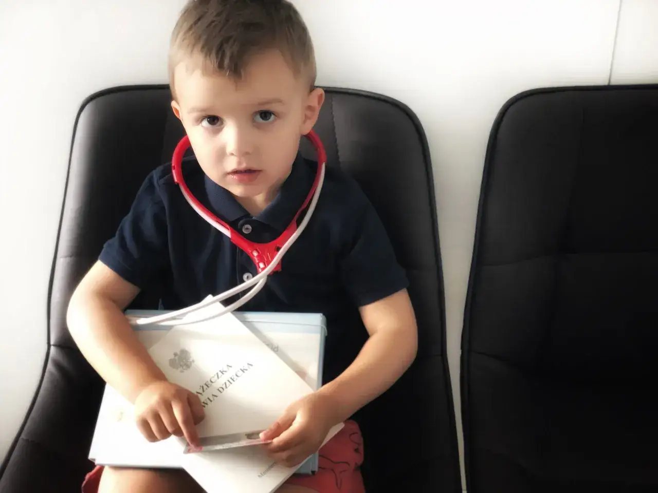 Chłopiec z zabawkami lekarskimi i dokumentami, zastanawia się, czy opieka nad dzieckiem przerywa urlop.