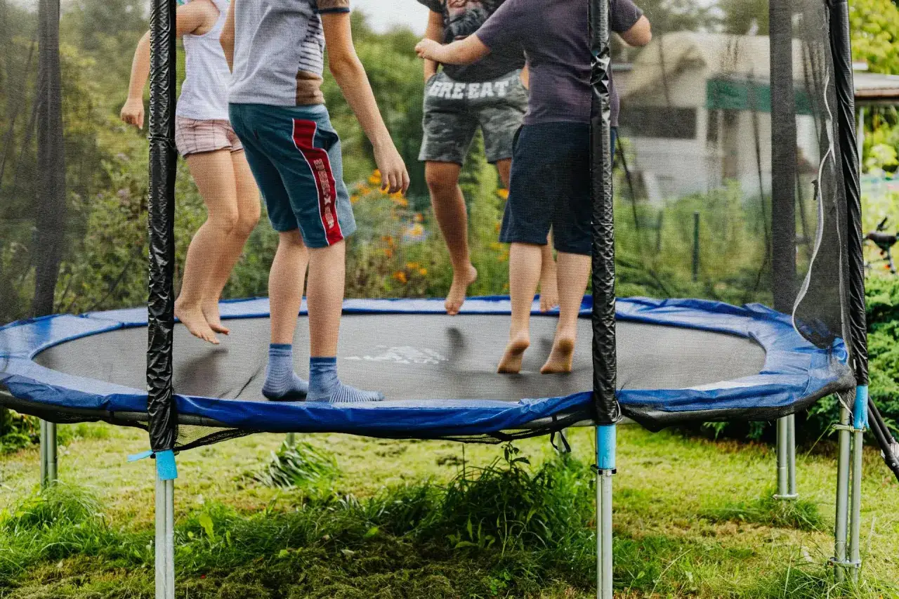 Dzieci skaczą na trampolinie, świetnie się bawiąc. Czy trampolina jest zdrowa? Z pewnością tak, bo to doskonała forma ruchu na świeżym powietrzu!