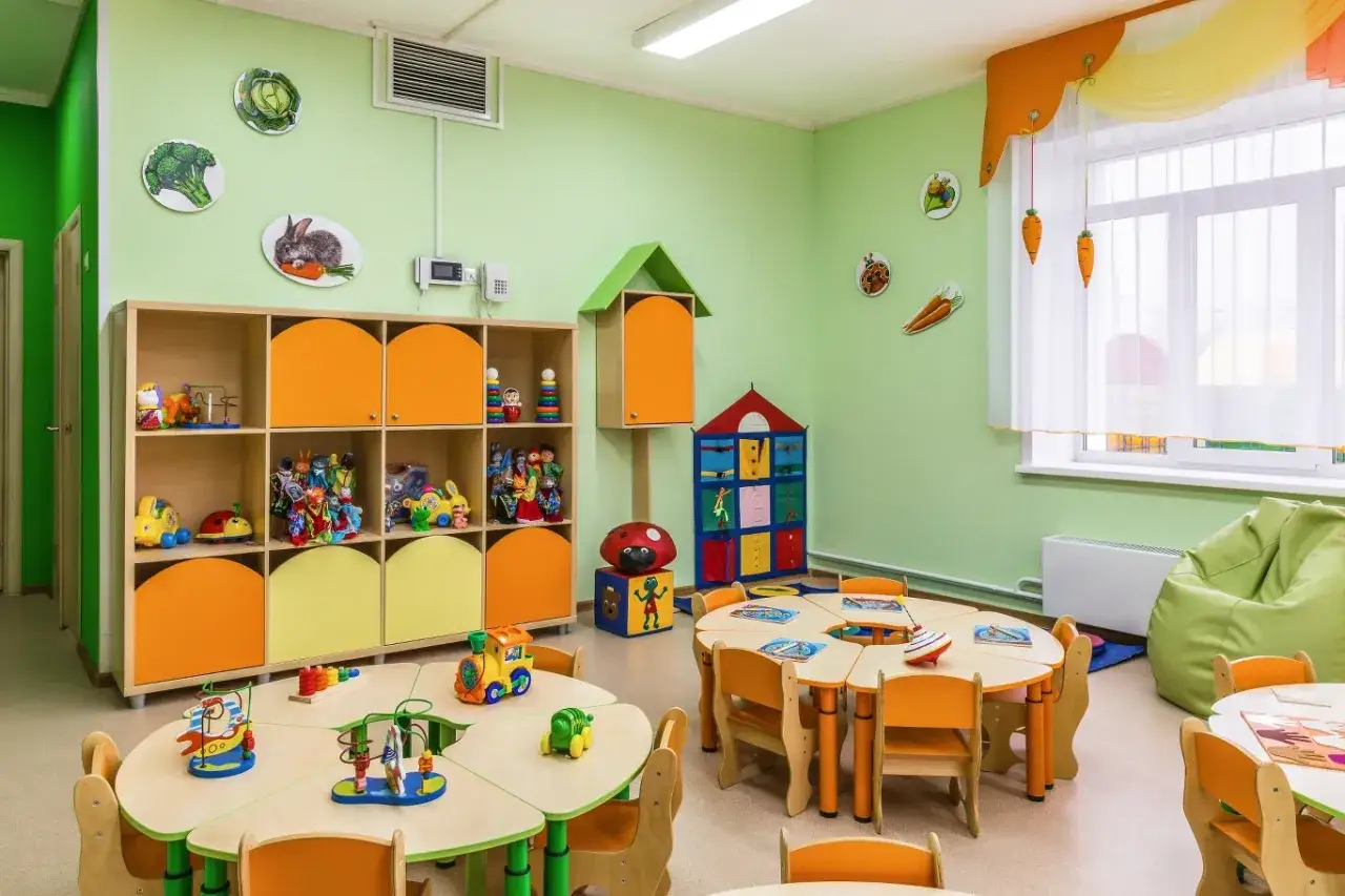 Kolorowa sala przedszkolna z zabawkami i stolikami. Zastanawiasz się, ile kosztuje żłobek miesięcznie?