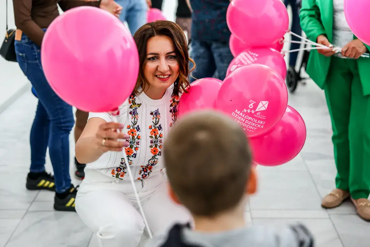 Uśmiechnięta kobieta z różowymi balonami, świętująca kiedy jest dzień dziecka.