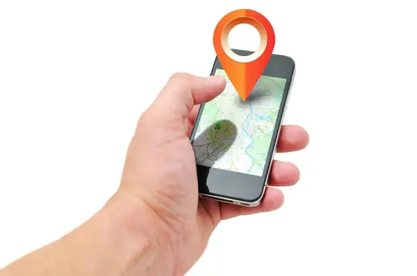 Dłoń trzyma smartfon z mapą i ikoną lokalizacji. Aplikacja pokazuje, jak działa lokalizator, gdzie jest dziecko.