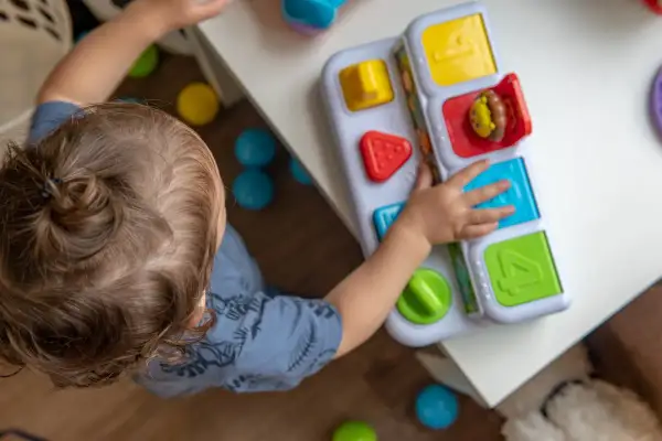 Dziecko bawi się zabawką edukacyjną. Zastanawiasz się, ile kosztuje żłobek miesięcznie?