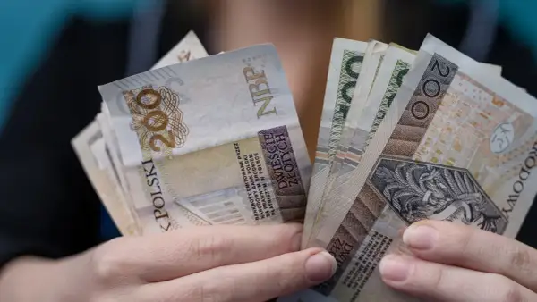 Ręce trzymające banknoty 200 zł. Czy to odpowiedź na pytanie, ile zarabia dyrektor żłobka?